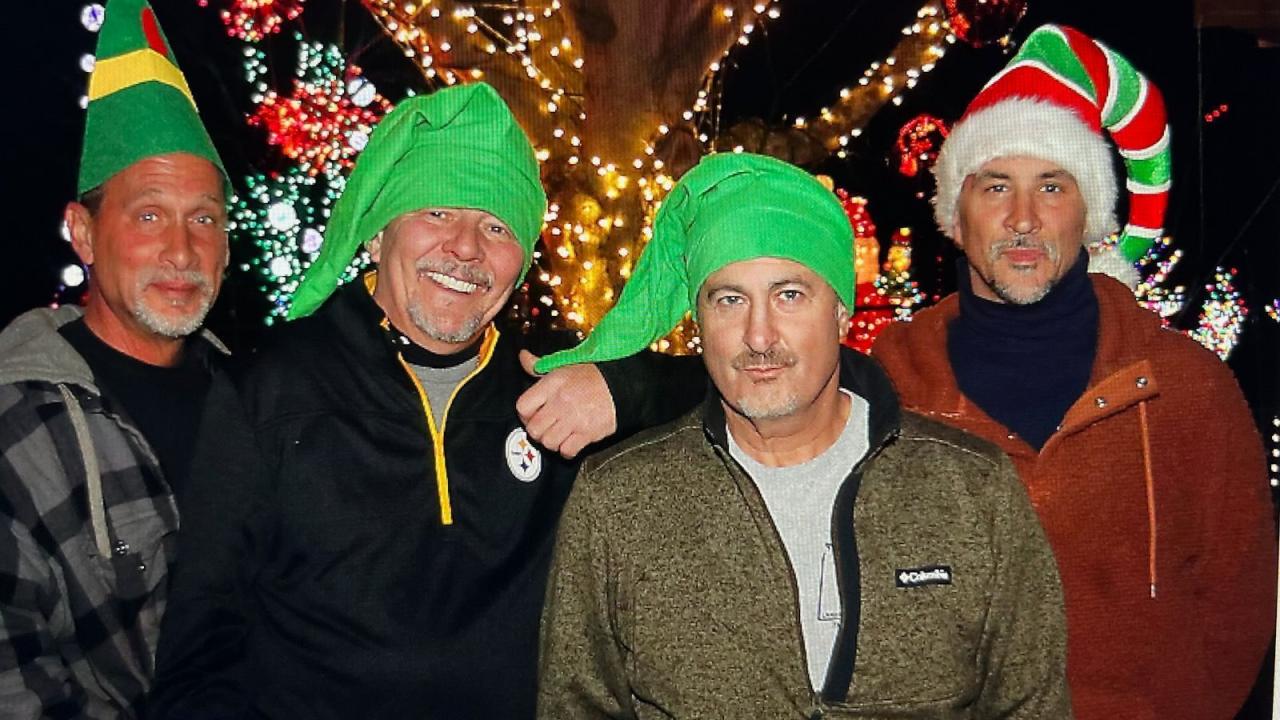Four friends in elf hats posing in front of the lights